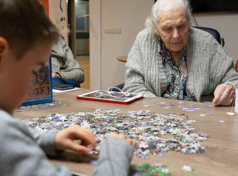 Great-grandmother playing with her great-grandson to do a puzzle