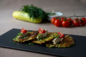 Zucchini pancakes with feta cheese, cherry tomatoes and herbs
