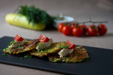 Zucchini pancakes with feta cheese, cherry tomatoes and herbs