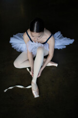 Ballerina sits and wraps pointe shoes