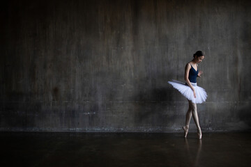 Fototapeta na wymiar Young ballerina stands leaning against the wall