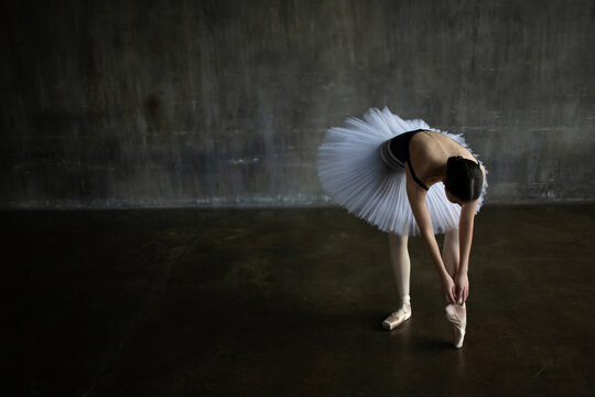 Ballerina adjusts her pointe shoes