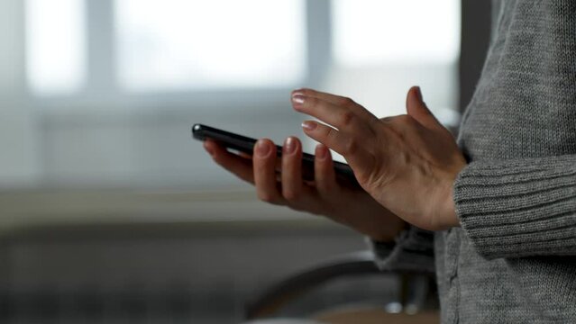 Woman hand using phone, indoors. Woman holding smartphone