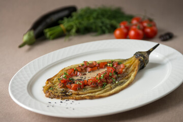 Eggplant baked with tomato and parsley on a white plate