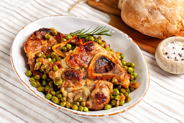Beef, veal ossobuco with green peas in a white plate.