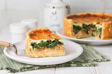 Slice of Spinach, cheese, onion and salmon fish tart or quiche.