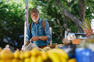 Senior man shopping at market in the city. Elderly man buying fresh vegetables and fruits from market stall.