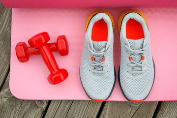 Karemat, sneakers and dumbbells on wooden background, top view