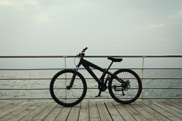 Black bicycle on wooden floor outdoors by the sea