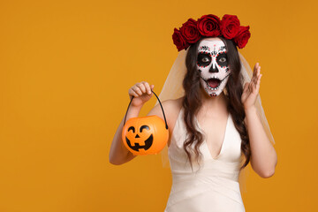 Emotional young woman in scary bride costume with sugar skull makeup, flower crown and pumpkin...