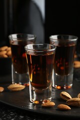 Glasses with tasty amaretto liqueur and almonds served on table, closeup
