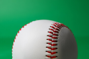 One baseball ball with stitches on green background, closeup