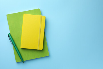 Different notebooks and pen on light blue background, top view. Space for text - Powered by Adobe