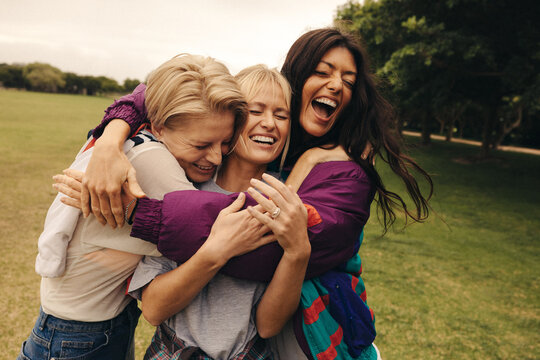 Friends hugging each other in park, sharing laughter and love outdoors