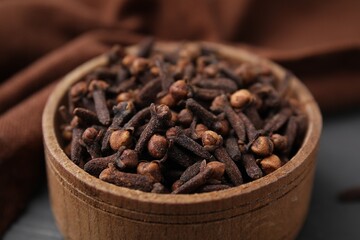 Aromatic cloves in bowl on table, closeup