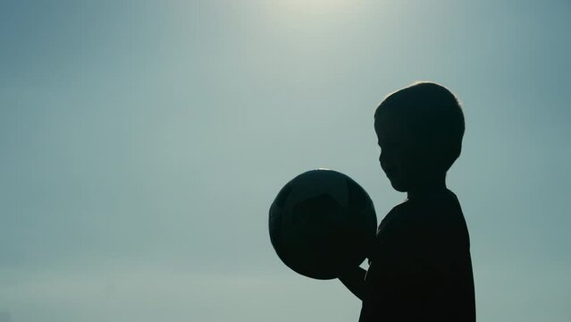 Silhouette of a Little Boy Holding a Ball in His Hands. Concept of Future Athlete, Aspiring Footballer, UEFA EURO 2024, FIFA World Cup