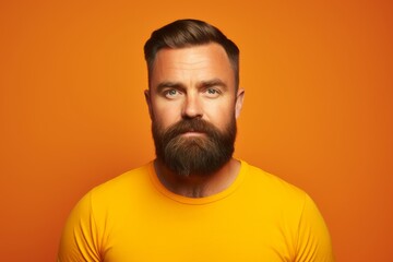 Serious man with beard and mustache looking at camera over orange background