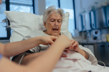 Nurse taking care of senior patient in intensive care unit. Senior woman after stroke, heart attack...