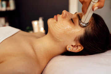 Closeup of face of beautiful relaxing girl undergoing hardware cosmetology procedure in spa