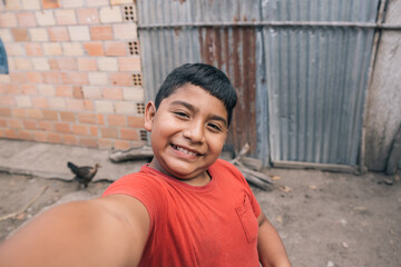 Latino child with red shirt smiles taking a selfie portrait