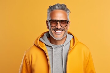 Portrait of happy middle-aged man in sunglasses and hoodie, isolated on yellow background