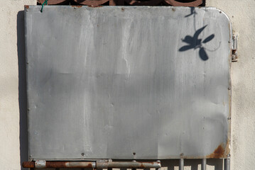 植物の影が映り込んでいる門に設置された薄い鉄板 - obrazy, fototapety, plakaty