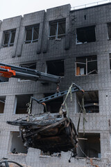 Loading the car onto a tow truck. Shahed blew up houses. A bombed residential building and burnt cars after the strike. War in Ukraine, the city of Dnipro. Burnt out car.