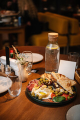 A light snack and appetizer on table. Served dinner table in cafe interior. Event festive dinner. Delicious dishes in restaurant. Serving table with food, birthday setting. Side view. Setup table.
