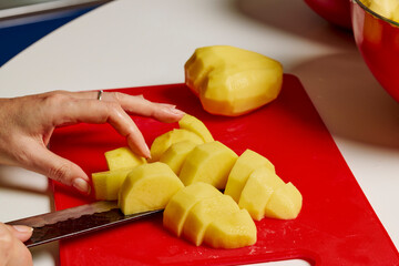 Woman's hands with a knife cutting potatoes to be cooked.
