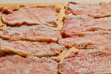 Pork tenderloin thinly sliced and prepared for schnitzel before cooking.