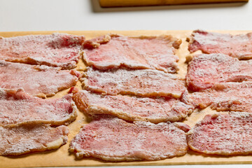 Pork tenderloin thinly sliced and prepared for schnitzel before cooking.