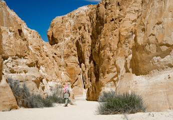 bedouin in white goes in the canyon in the desert among the rocks in Egypt Dahab South Sinai