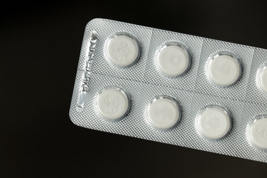 White round paracetamol pills in a silver strip on a black background. Medical health care concept.