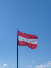 Österreichische Flagge im Wind vor blauem Sommerhimmel
