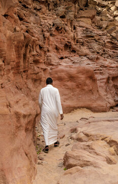 man in white arab clothing walks in a colored canyon in Egypt Dahab South Sinai