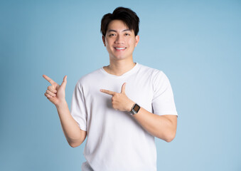 Portrait of Asian guy posing on blue background