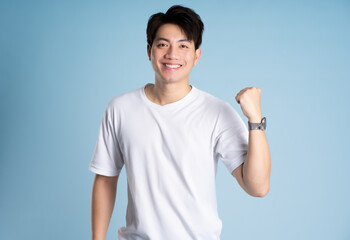 Portrait of Asian guy posing on blue background