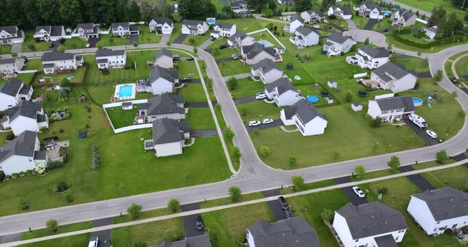 Aerial view of private residential houses in rural suburban sprawl area in Rochester, New York. Upscale suburban homes with large backyards and green grassy lawns in summer season