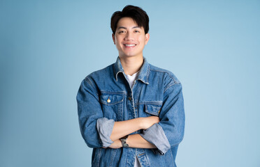 Portrait of an Asian guy wearing a jacket posing on a blue background