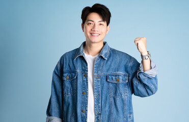 Portrait of an Asian guy wearing a jacket posing on a blue background