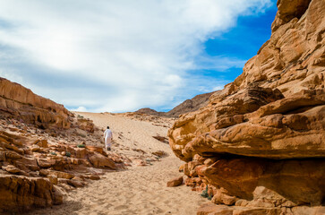 Fototapeta na wymiar man in white arab clothing walks in a colored canyon in Egypt Dahab South Sinai