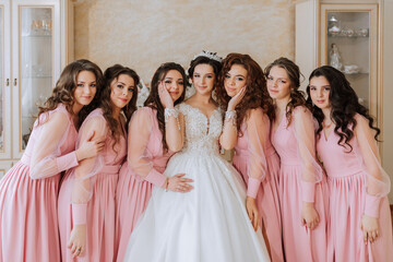 Portrait of the bride with her friends in the room. A brunette bride in a long white dress and her...