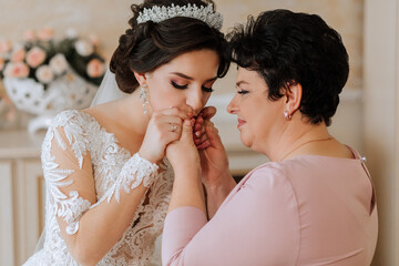 A beautiful and happy mother and her daughter, the bride, are standing next to each other. The best...