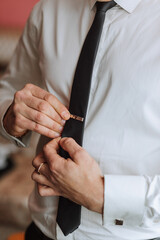 man's tie in hands, close-up photo of hands. The groom is preparing for the ceremony. Last...