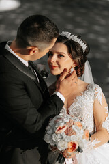 Wedding couple in love. A beautiful bride and an elegant groom tenderly embrace and enjoy the day. A stylish couple of newlyweds. Concept of marriage