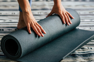 Yoga at home active lifestyle woman rolling exercise mat in living room for morning meditation yoga...