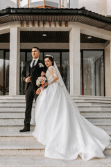 Fototapeta premium Wedding couple in love. A beautiful bride and an elegant groom tenderly embrace and enjoy the day. A stylish couple of newlyweds. Concept of marriage