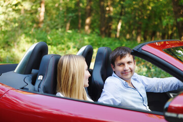 Couple in red cabriolet in a sunny day