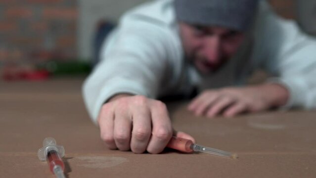A drug addict reaches for a dose of drugs in a syringe. Drug addiction concept.