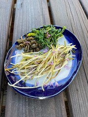 fresh wild foraged vegetables on a blue and white plate